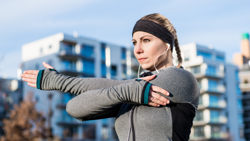 Woman performing a shoulder stretch during an outdoor stretching session.